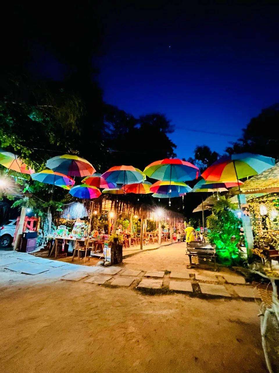 Caminho de entrada do Dedo de Moça Café da Roça ao entardecer, sob os guarda-chuvas coloridos